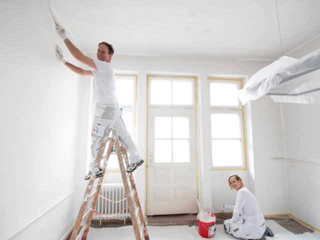 Maler streicht die Decke eines hellen Wohnraums